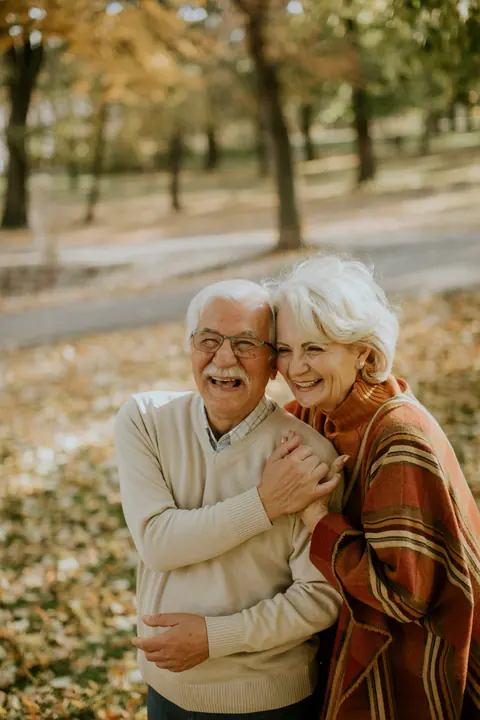 An older couple embracing in an autumn park