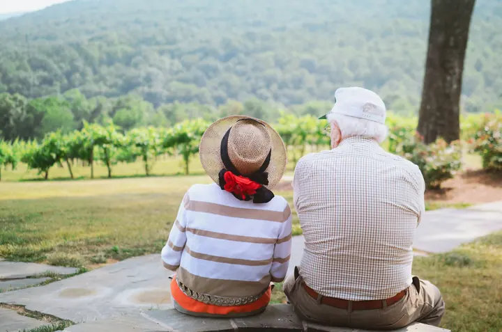 An older couple sitting together looking out over hills